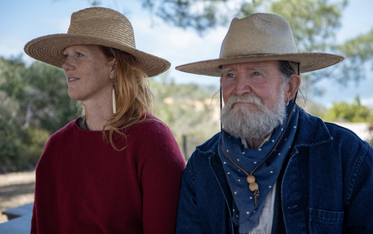 Kimberly Ann Johnson and Stephen Jenkinson outdoors in sun hats